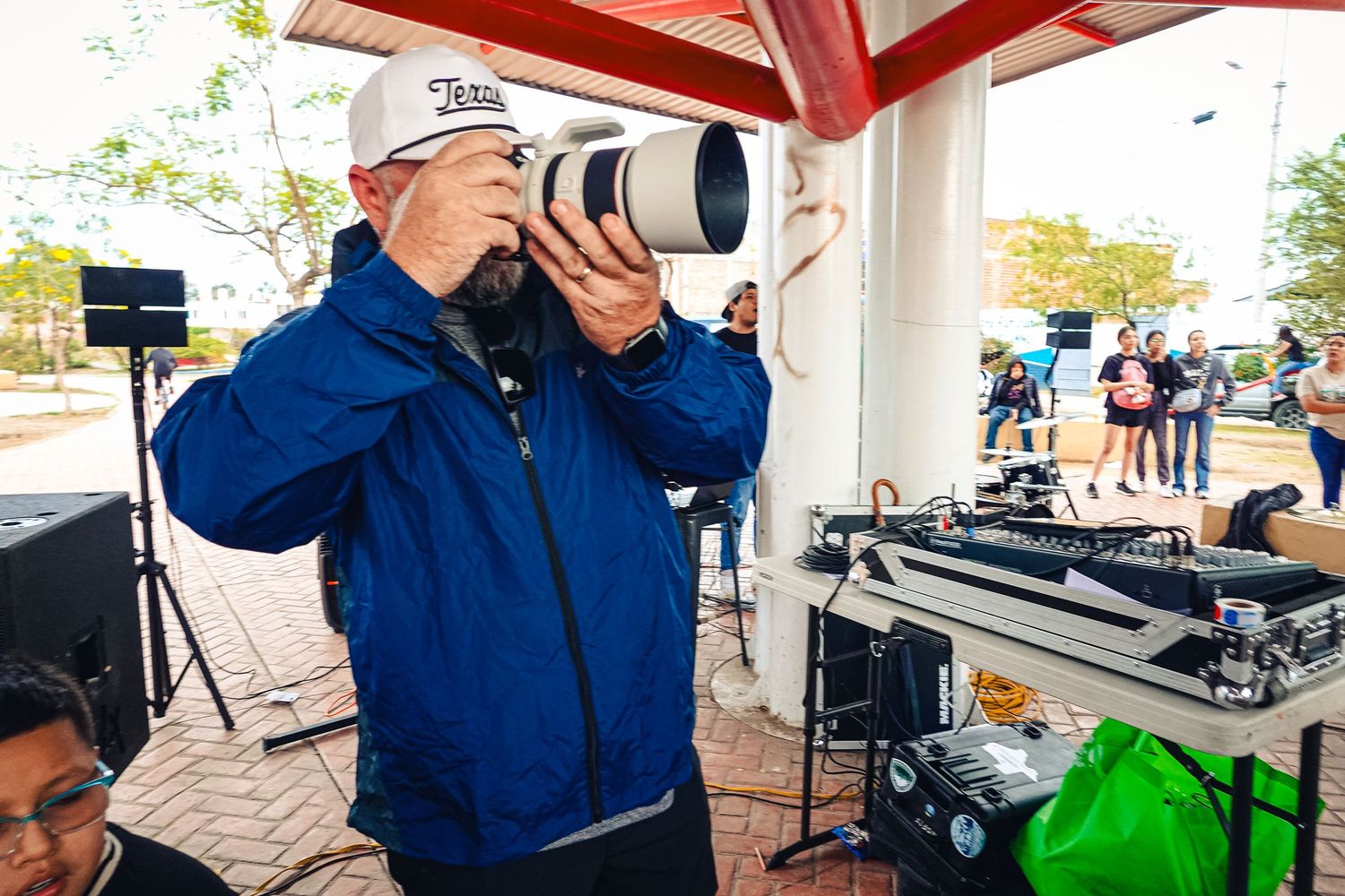 Photographer using professional camera with long telephoto lens at outdoor event.
