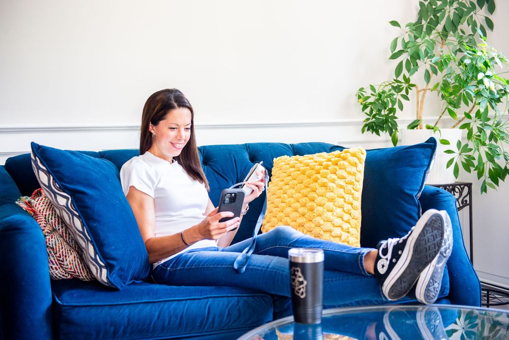 Person relaxing on blue couch reading with feet up.