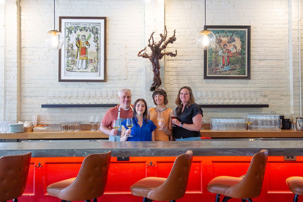 Bar interior with red seats and vintage artwork on white brick walls.