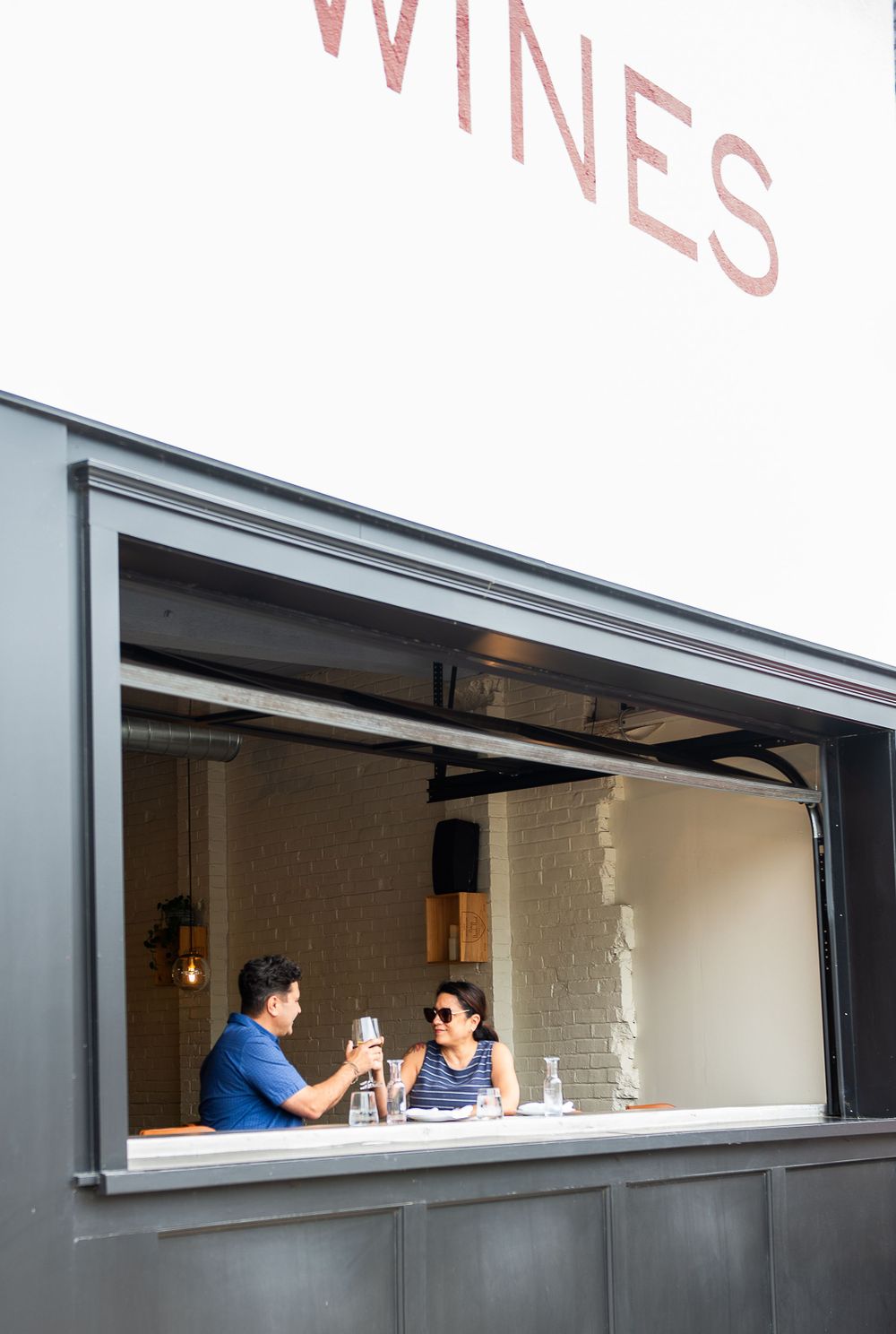 Wine bar service window with customers visible through opening.