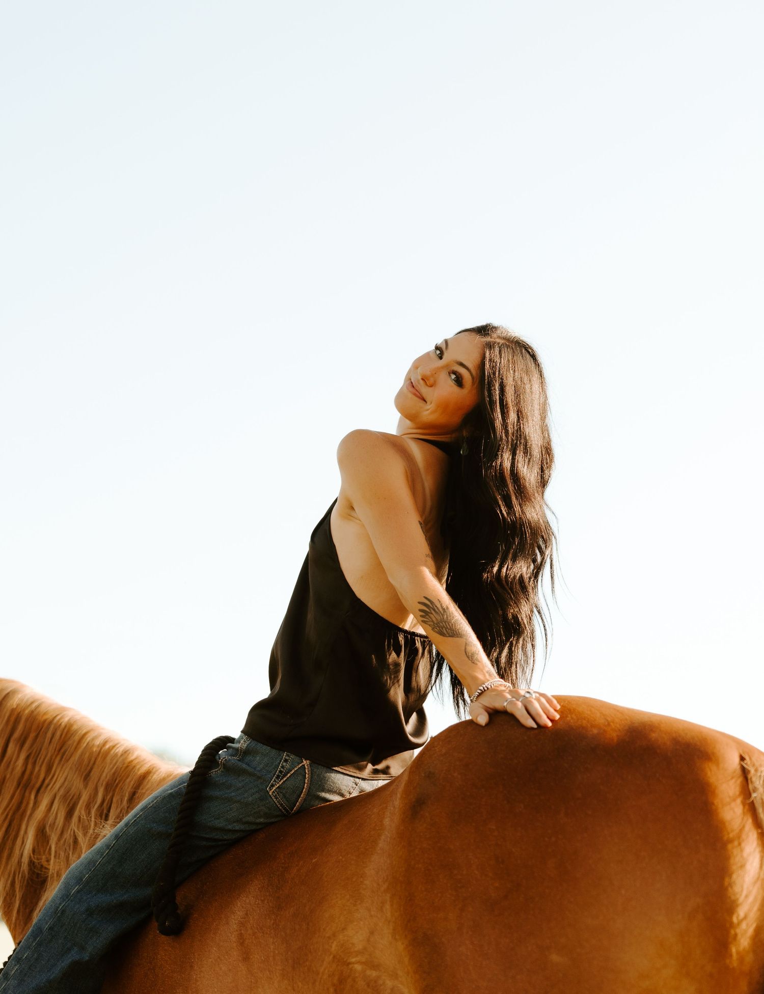 Senior lying back on brown horse during seniors photos in Gallatin, TN.