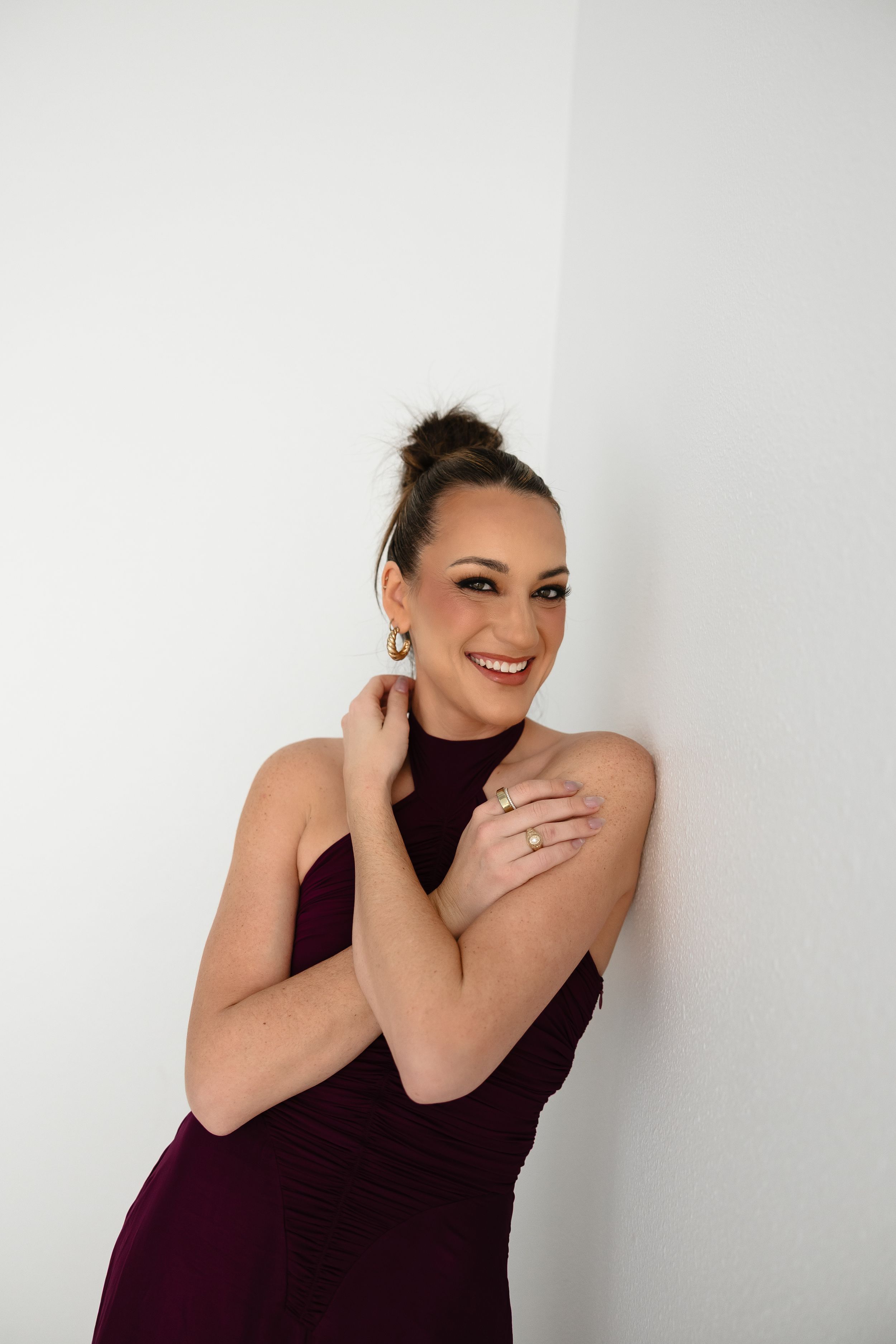 Professional photographer wearing black holding a camera and laptop against white background.