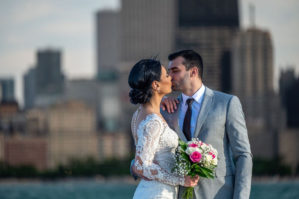 A bride and groom share romantic kisses against a city skyline backdrop in a series of wedding photos.