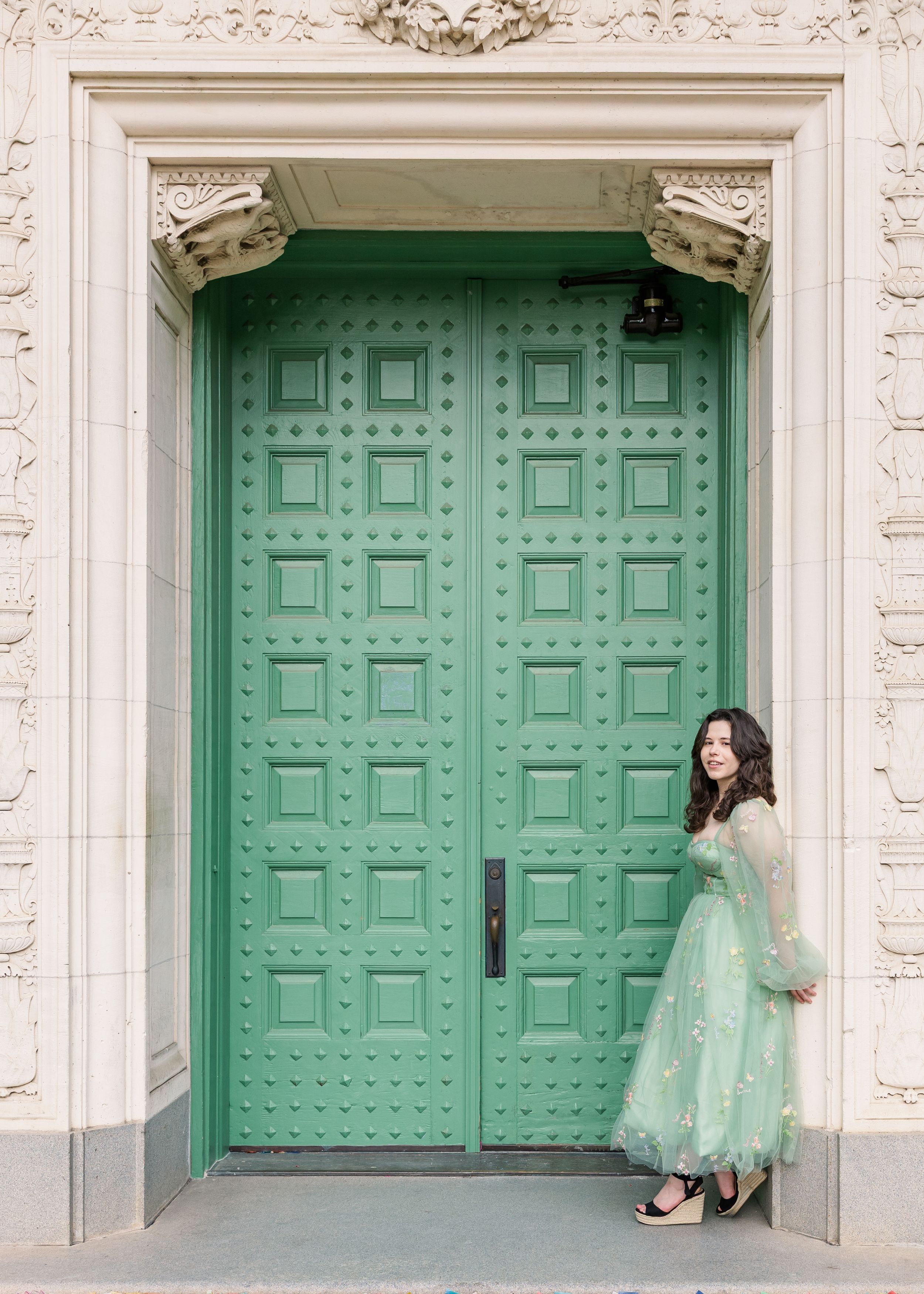 A series of three turquoise doors with ornate white stone framing in a classical architectural setting.