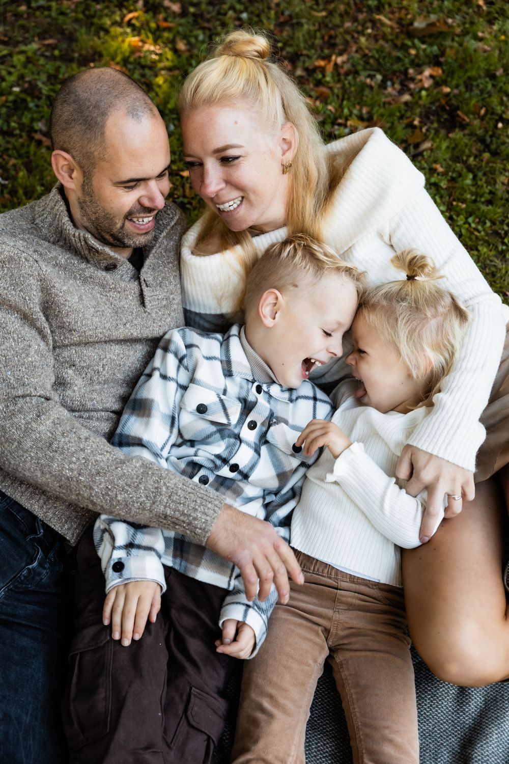 A loving family shares tender moments and laughter while sitting together outdoors in autumn.