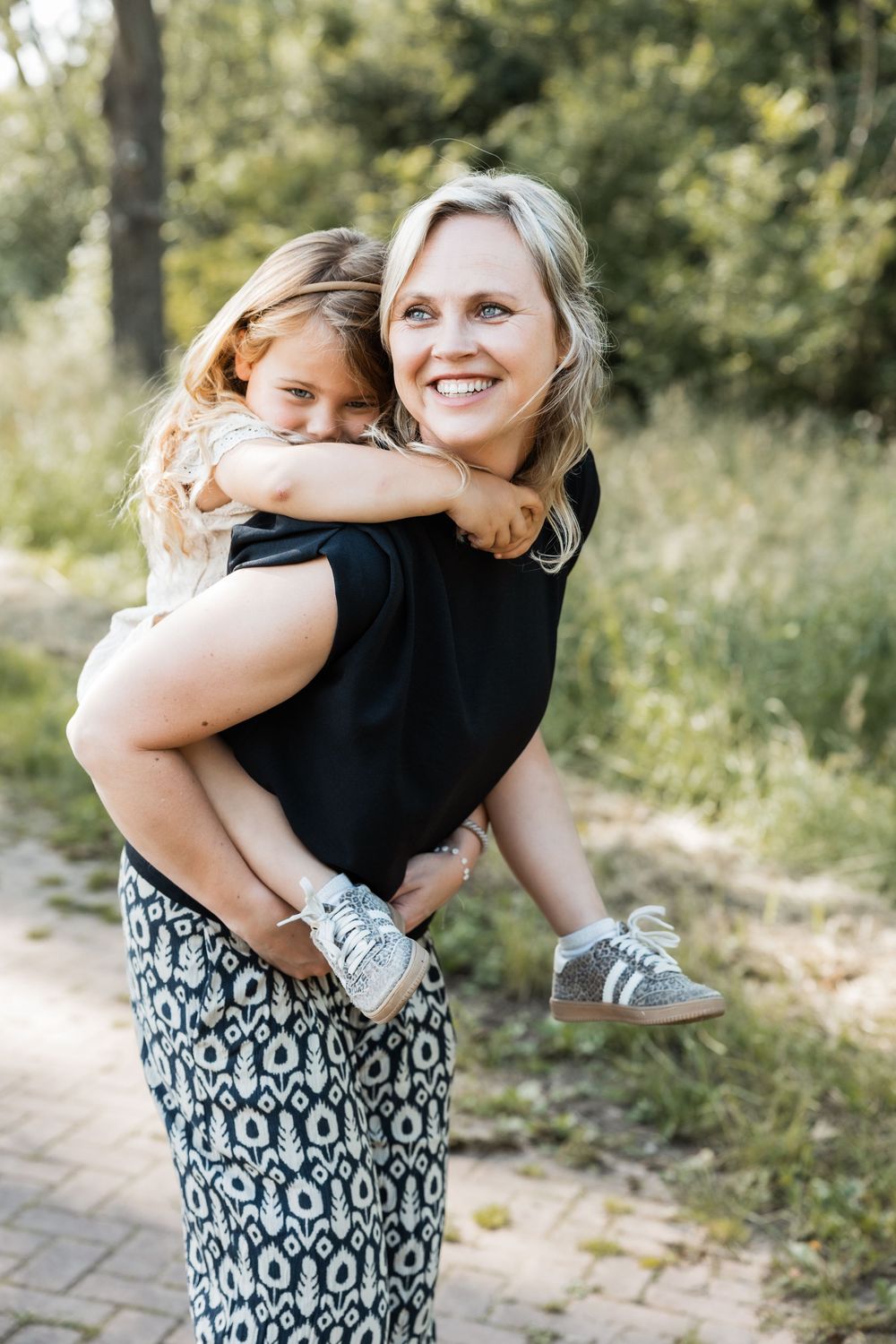 A heartwarming series of embrace photos taken outdoors with a black and white patterned dress against natural foliage.