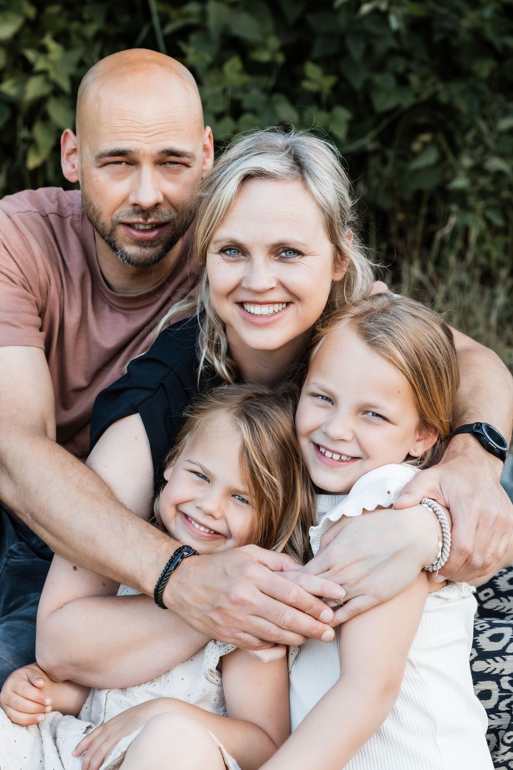 A joyful family moment captured in a series of candid black and white outdoor portraits showing warm embraces and smiles.