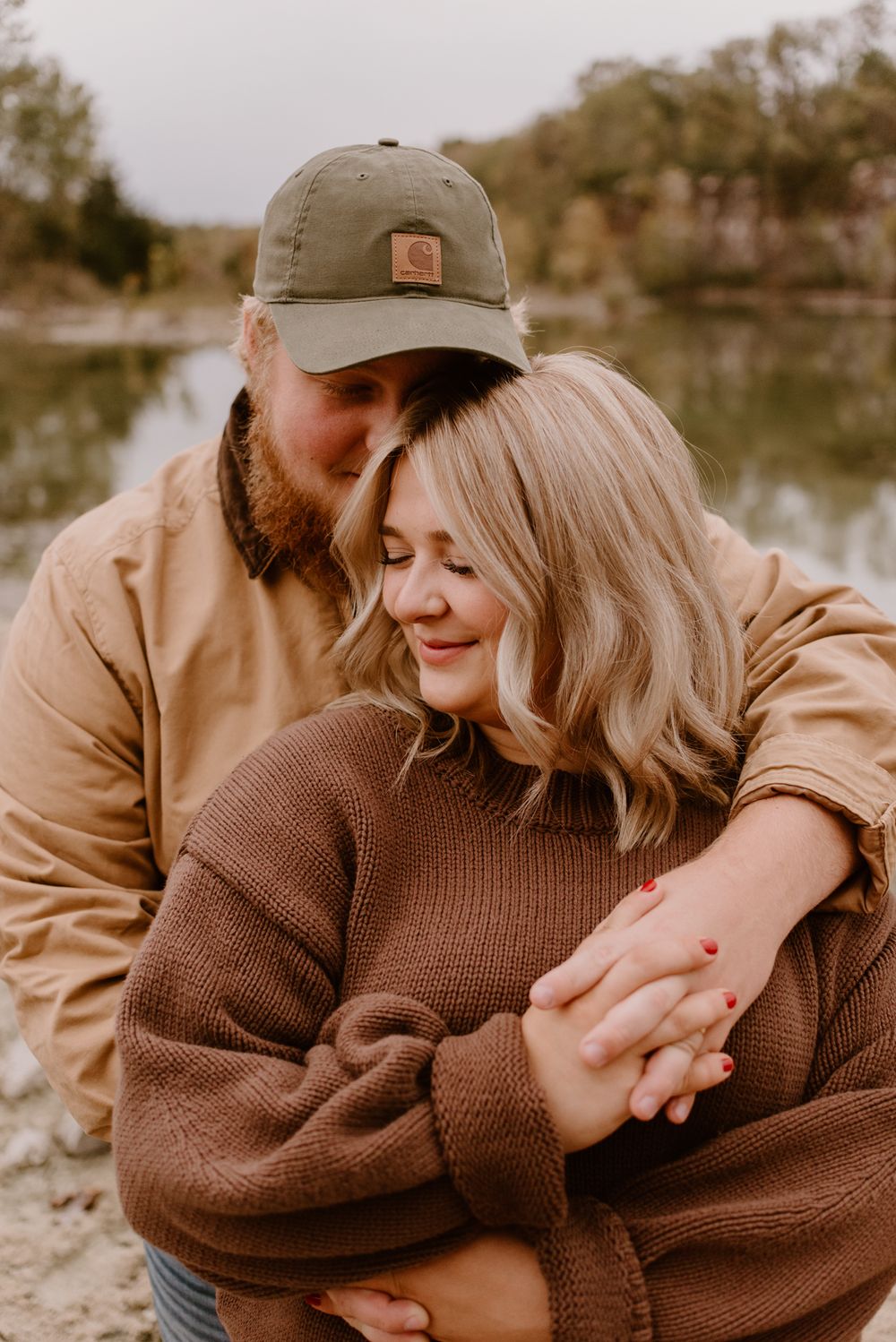 Sweet candid moments between a couple in casual fall attire by a serene lakeside.