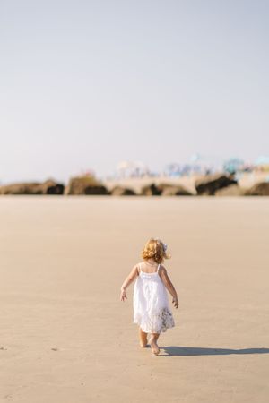 A series of photos showing a person in white dress sitting on a sandy beach, getting progressively smaller in each frame.