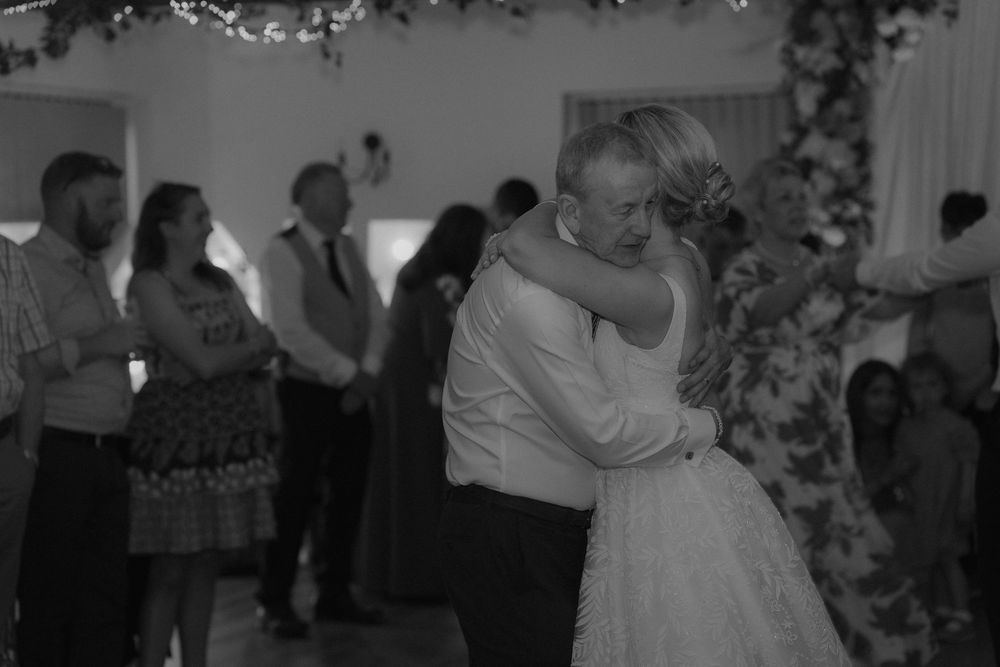 Black and white photo of a bride and groom sharing an emotional first dance at their wedding reception.
