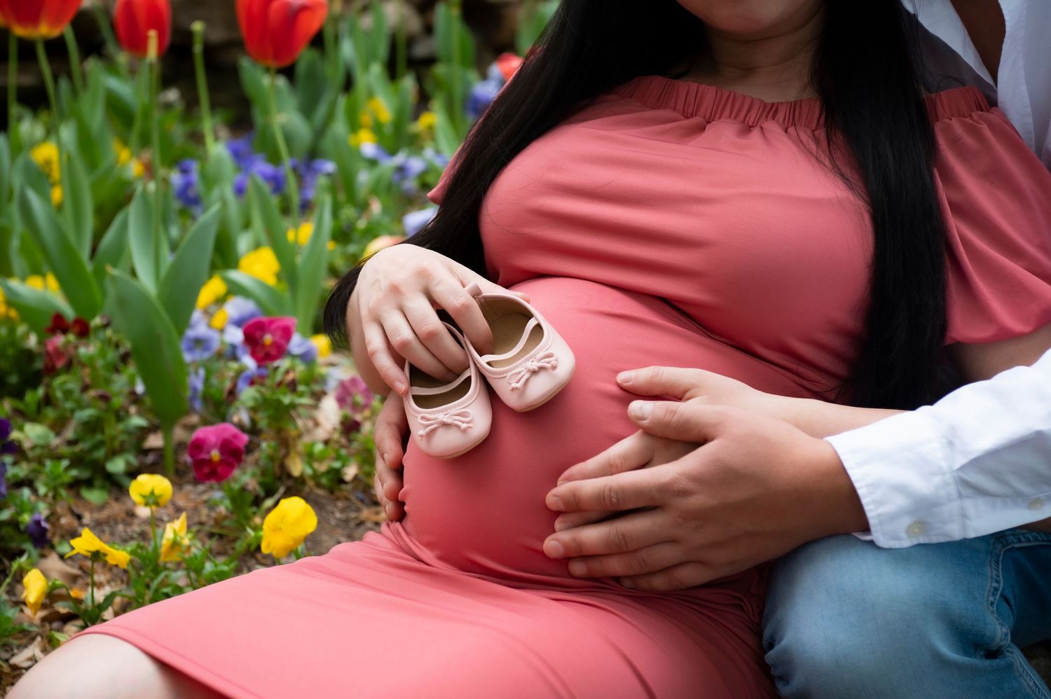 Couple sitting among colorful spring tulips and flowers in garden setting.