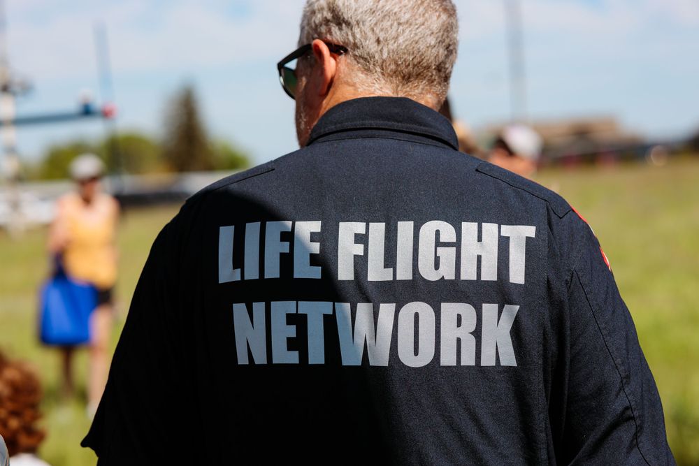 A man in a Life Flight Network shirt walks through a grassy field, enjoying the outdoors and the fresh air.
