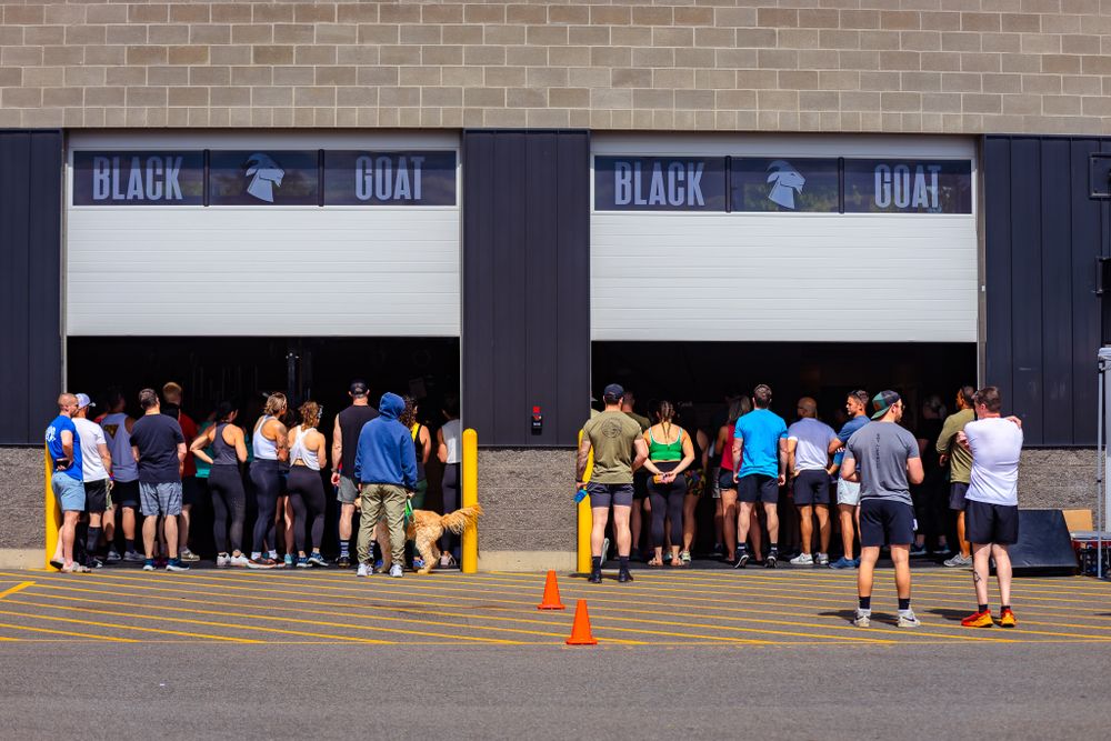 Individuals of various backgrounds standing in line outside a structure, reflecting a moment of gathering and patience.