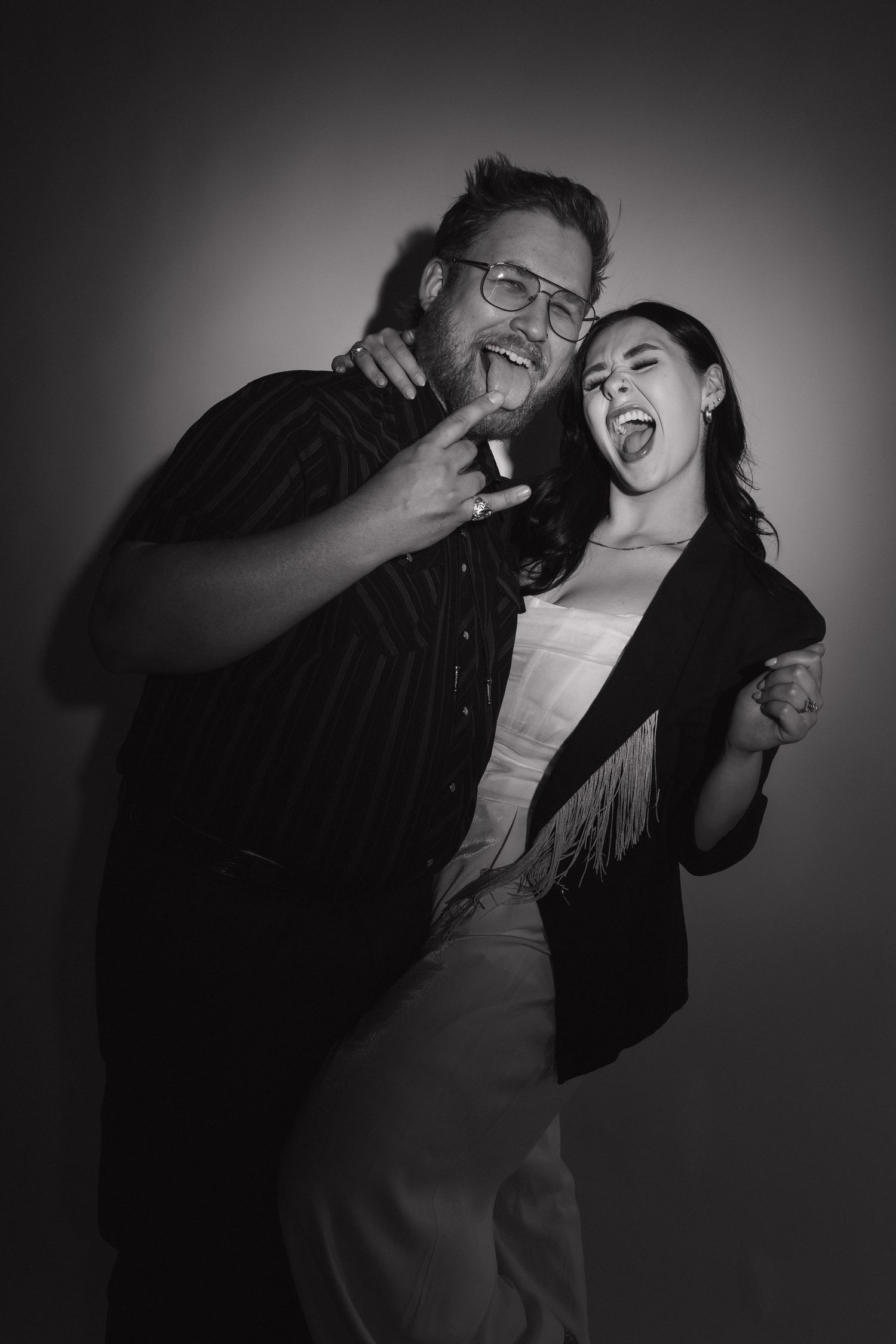 A playful black and white studio portrait of two photographers making energetic expressions.