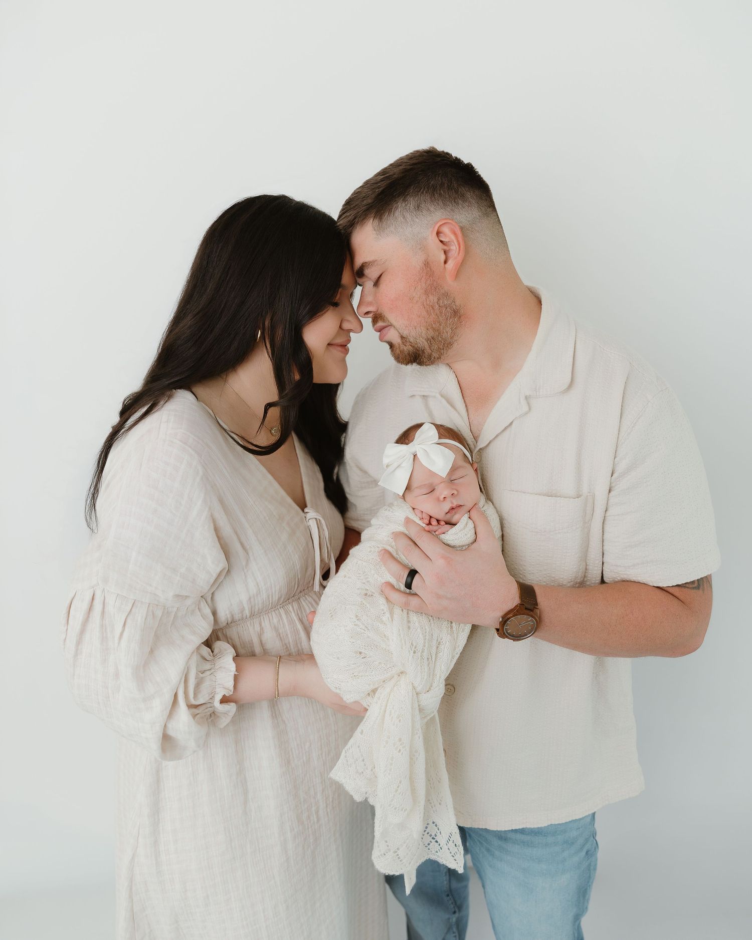 Mother and father embracing their newborn in a timeless family portrait. Newborn Photography Session Tyler Texas