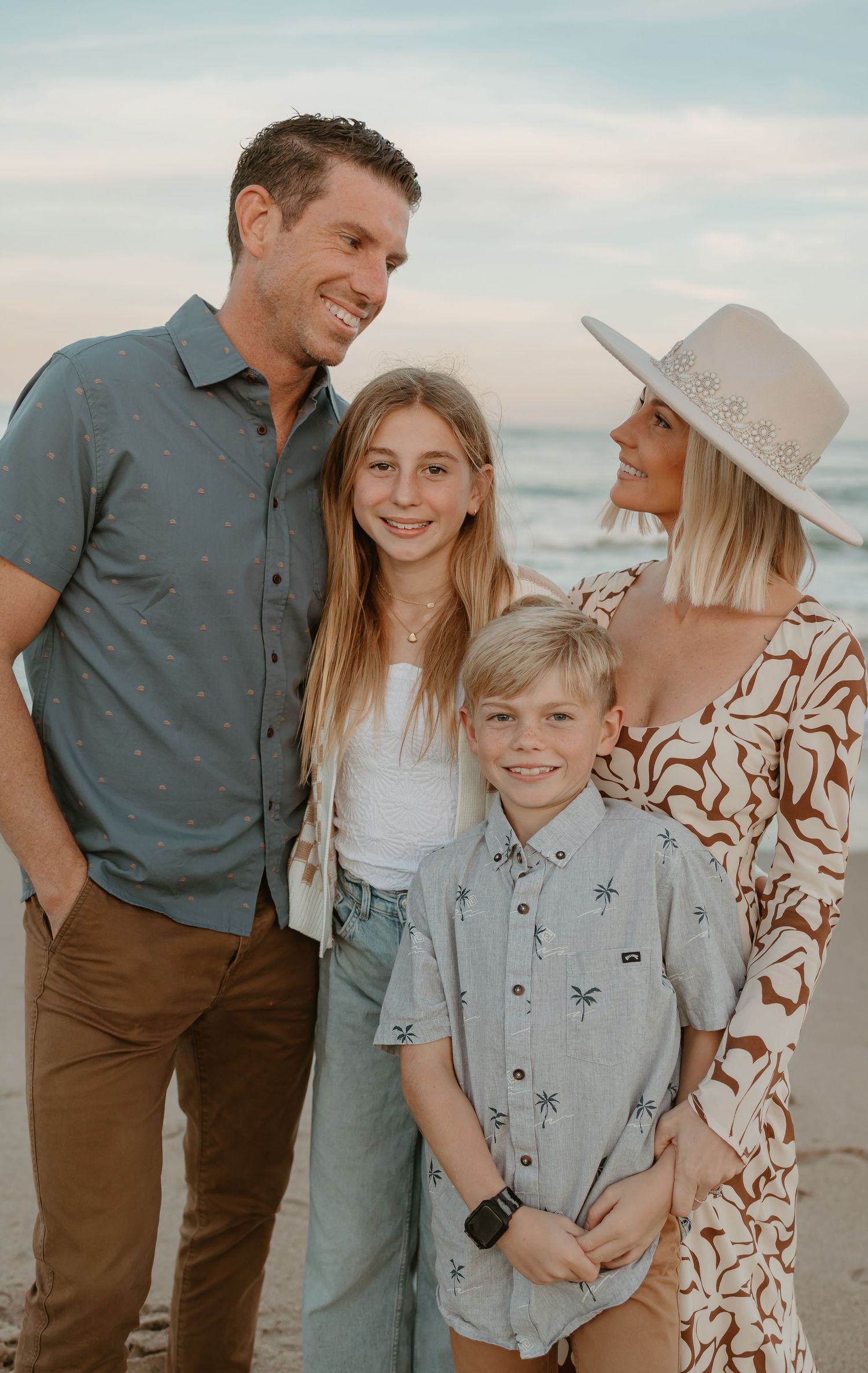 Small group poses casually together on beach during sunset photo session.