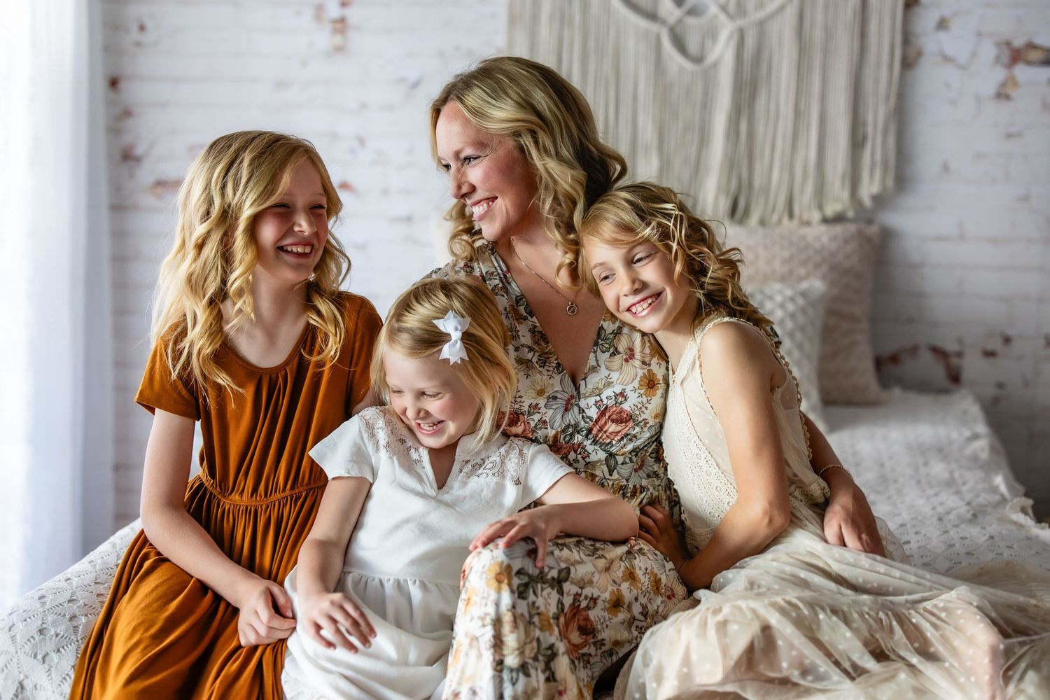 A group of people sit together on a couch laughing and sharing joyful moments in a bright, airy room.