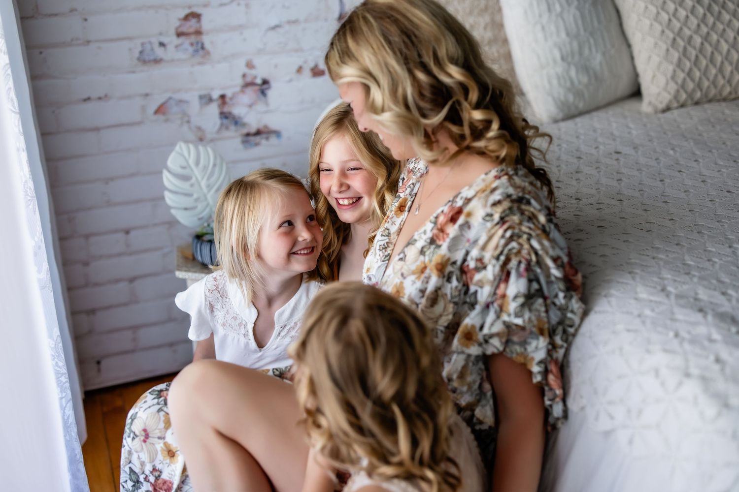 A series of candid moments between a mother and daughter sharing laughter and embraces on a white bed.