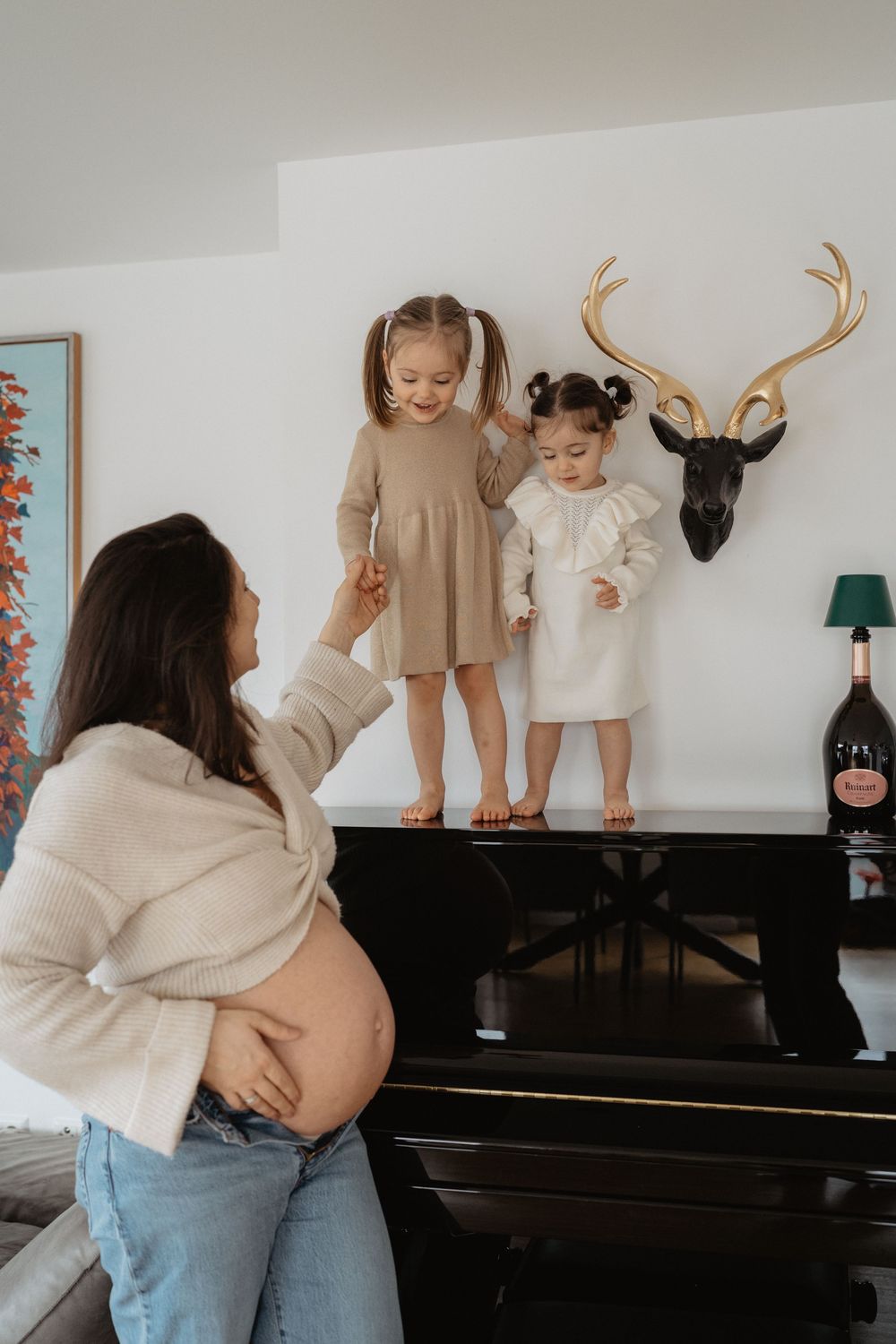 Family maternity photos taken by a piano showing playful interaction between mother and child.