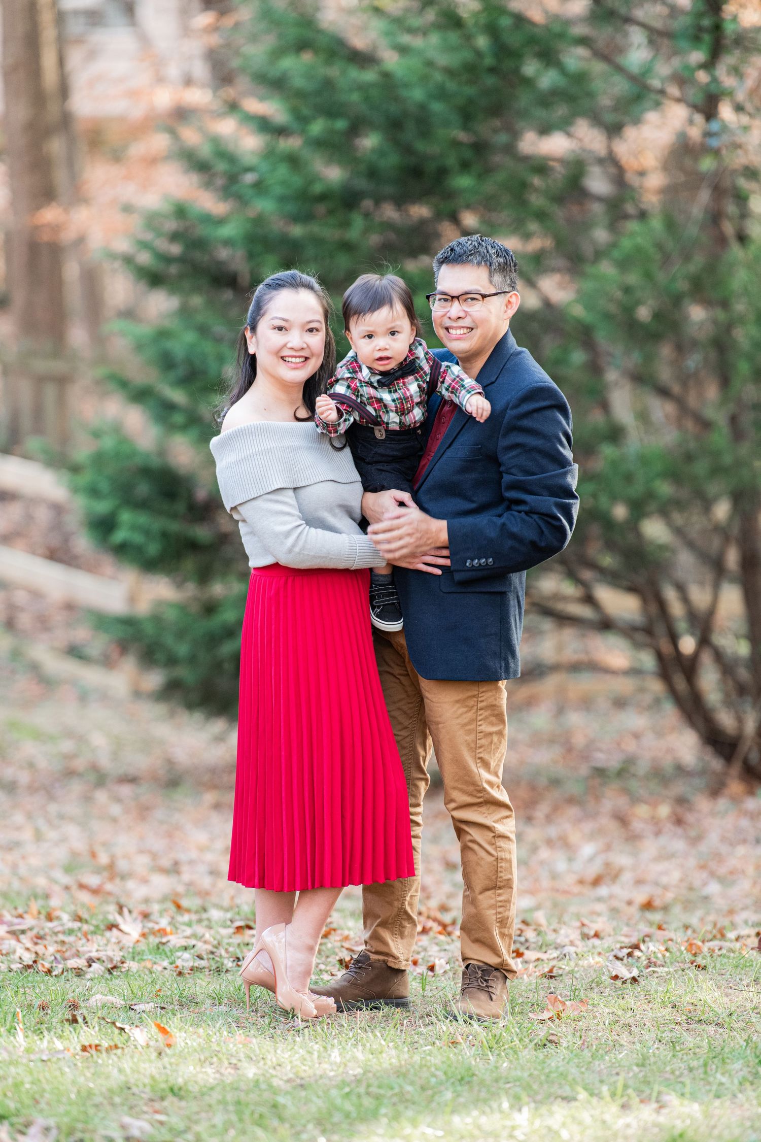 Lovely young parents holding their happy, sweet baby for the holidays, set against a beautiful, natural background.