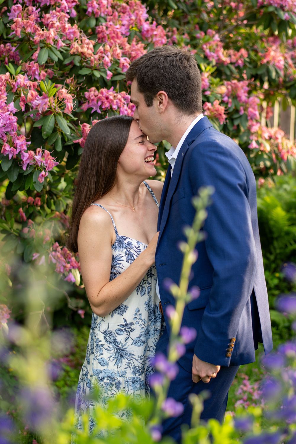 Couple kissing among colorful flowers during romantic golden hour engagement portraits at Minuteman Park in Concord, Massachusetts