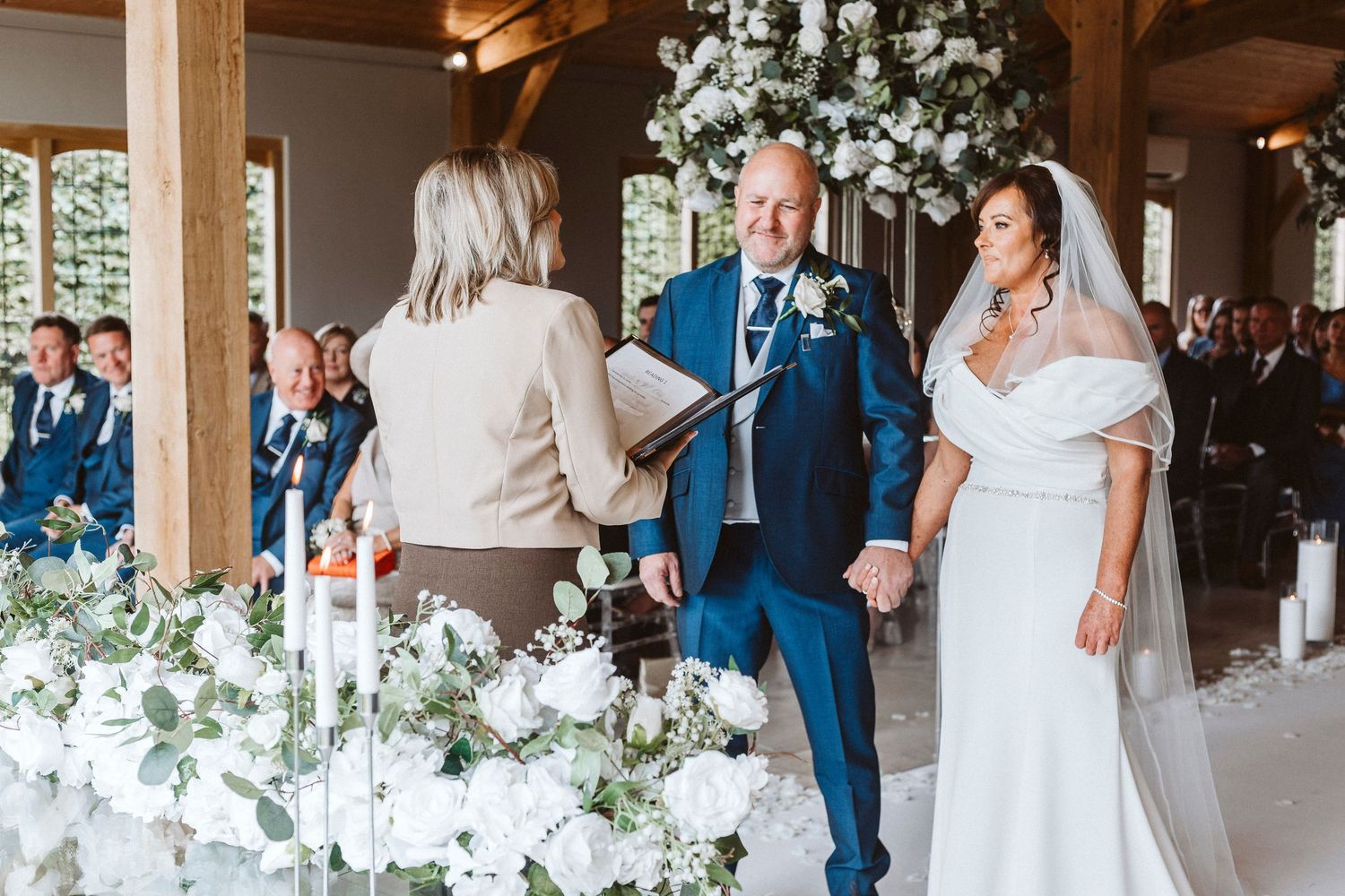 Bridesmaids in navy dresses taking shots with bouquets at elegant indoor reception.