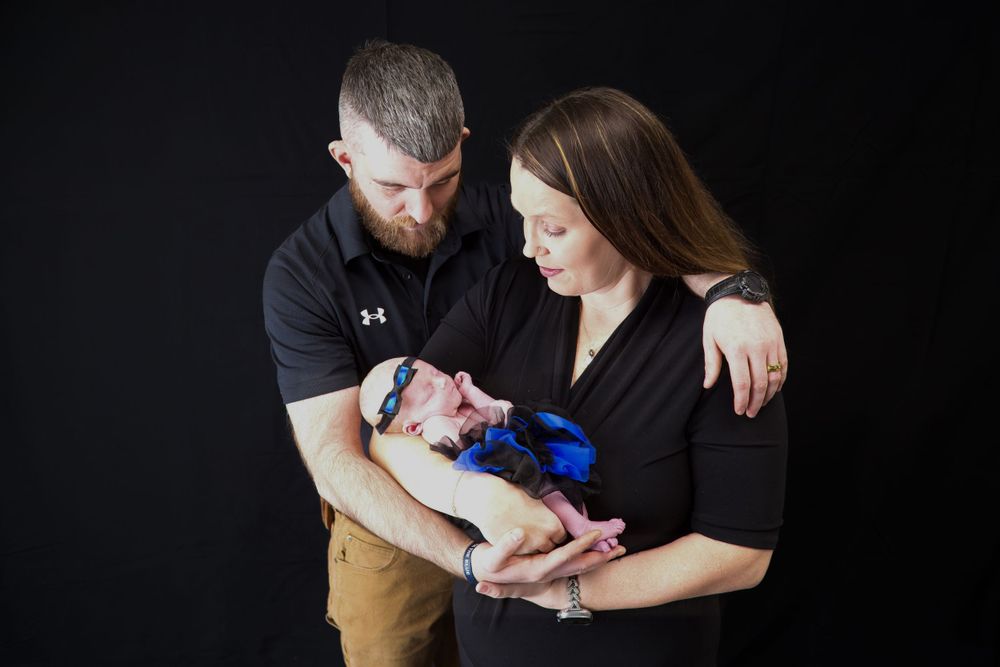 Professional family portrait of two parents looking lovingly at their newborn baby.
