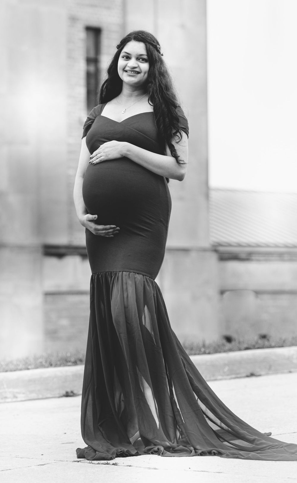 A person in a flowing black dress poses outdoors in a series of black and white photos showing different angles and poses.