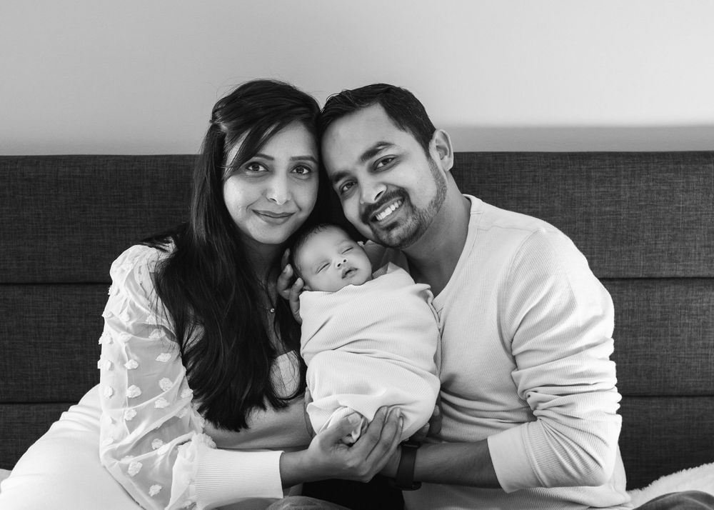 Black and white portrait of a family with their newborn baby in a tender moment together.