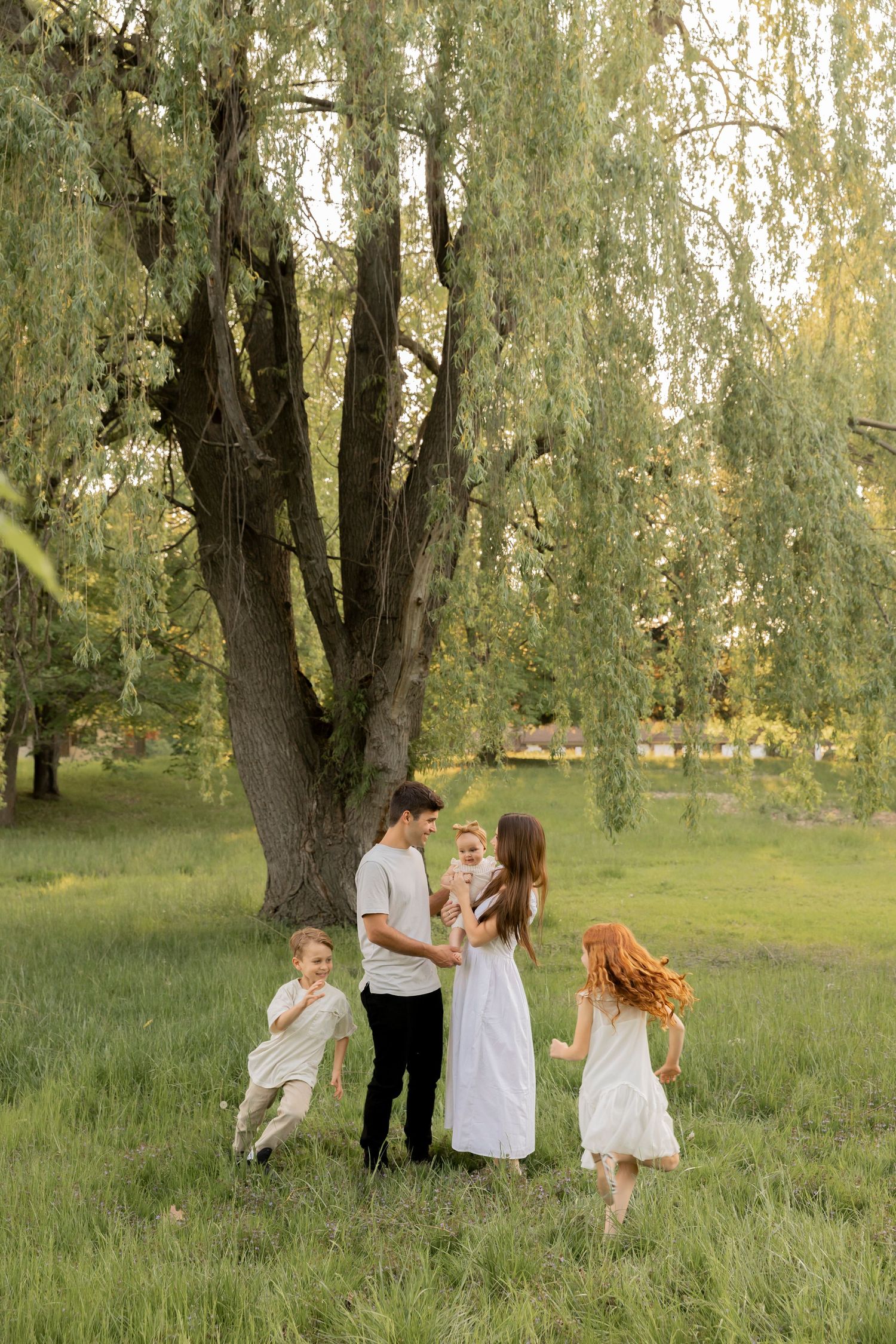 family playing with their children in front of a large willow tree in Oakland county