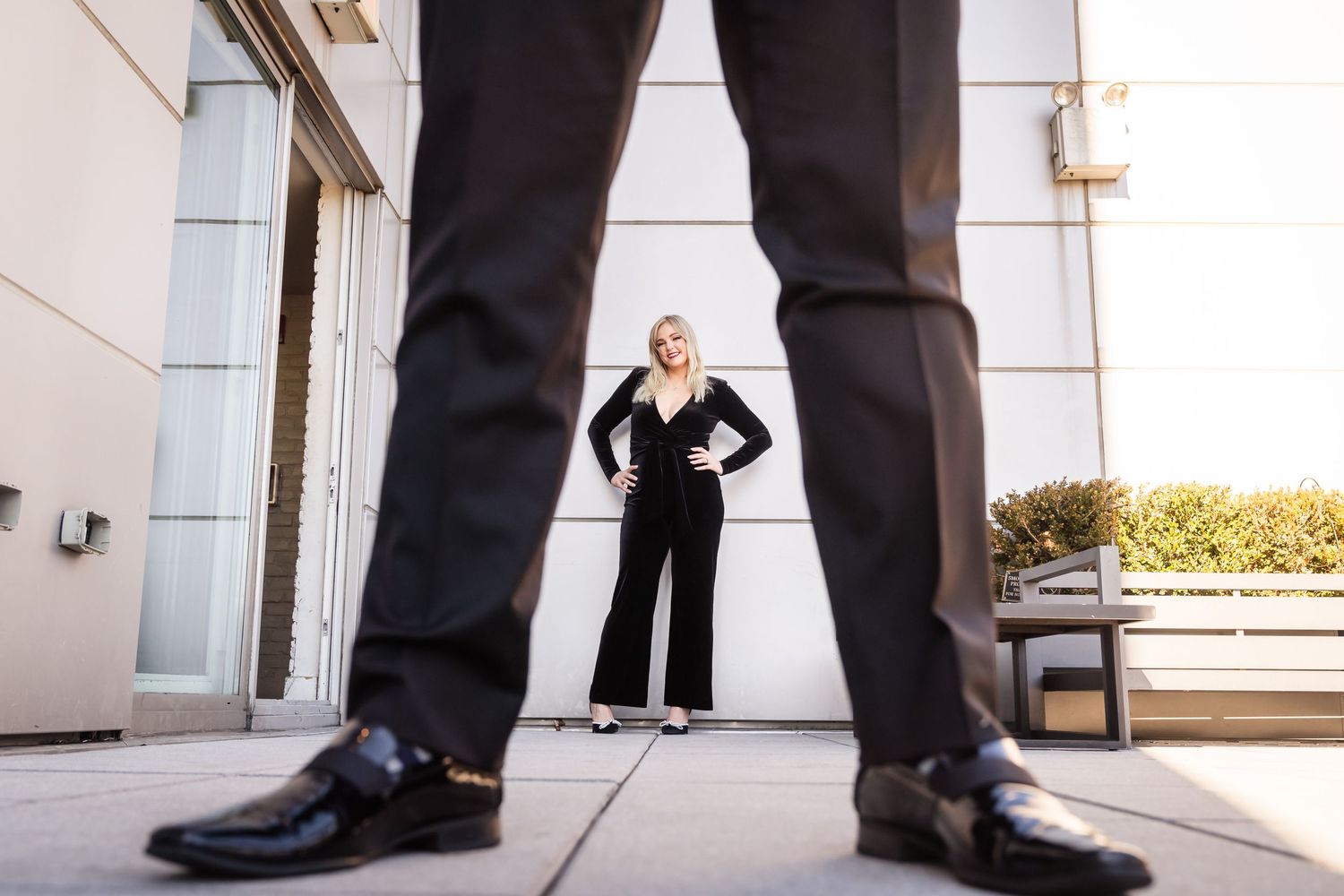 Creative low angle shot through black dress shoes showing business attire figure standing confidently in office doorway.