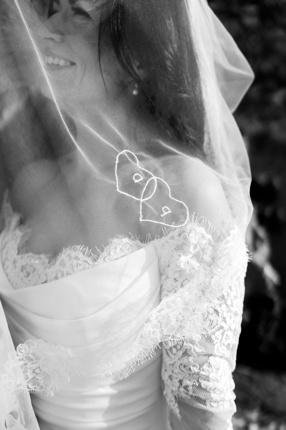 Close-up details of delicate white lace and fabric on a wedding dress sleeve against a dark background.
