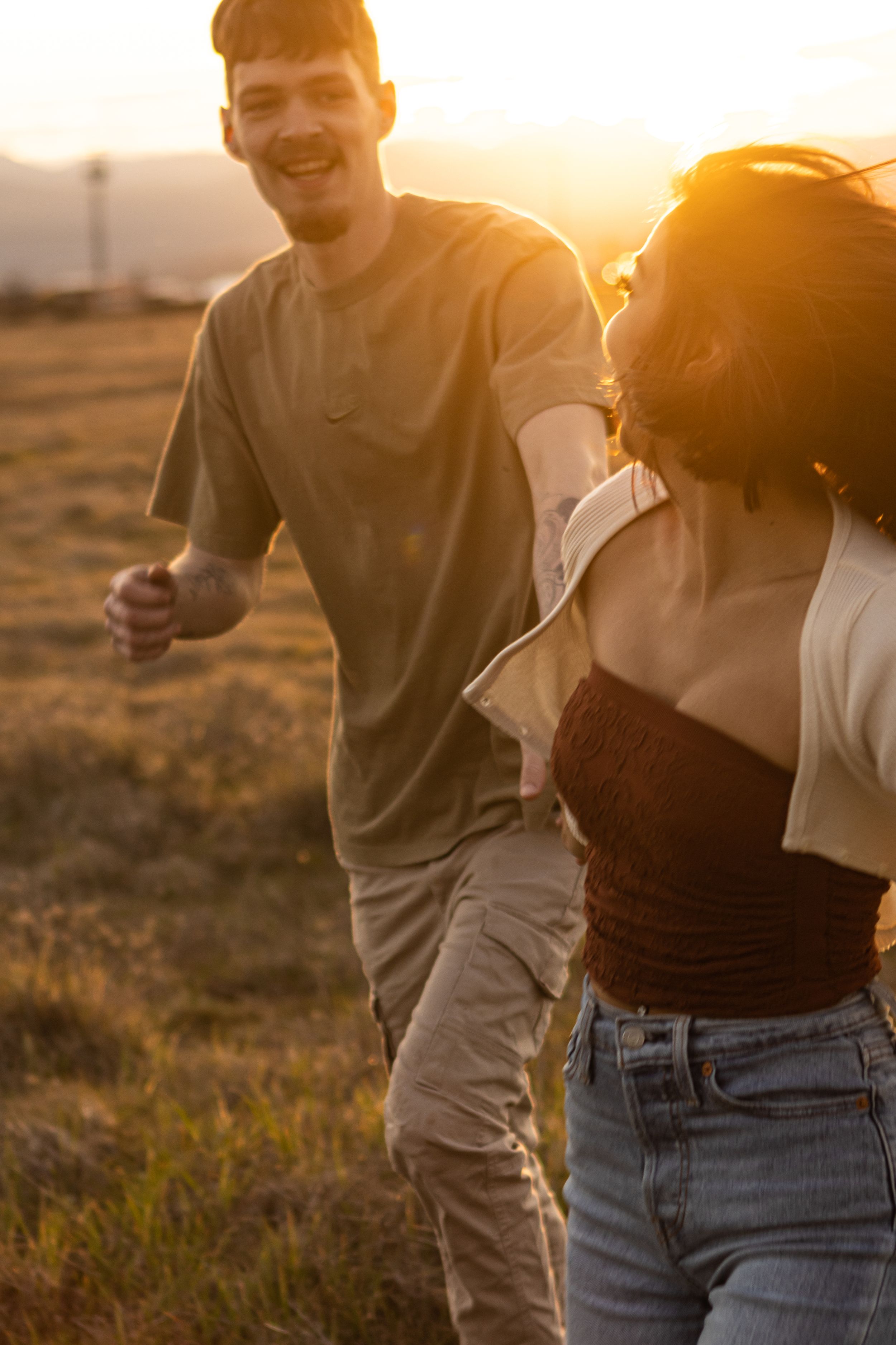 There is a couple running in the sunset together