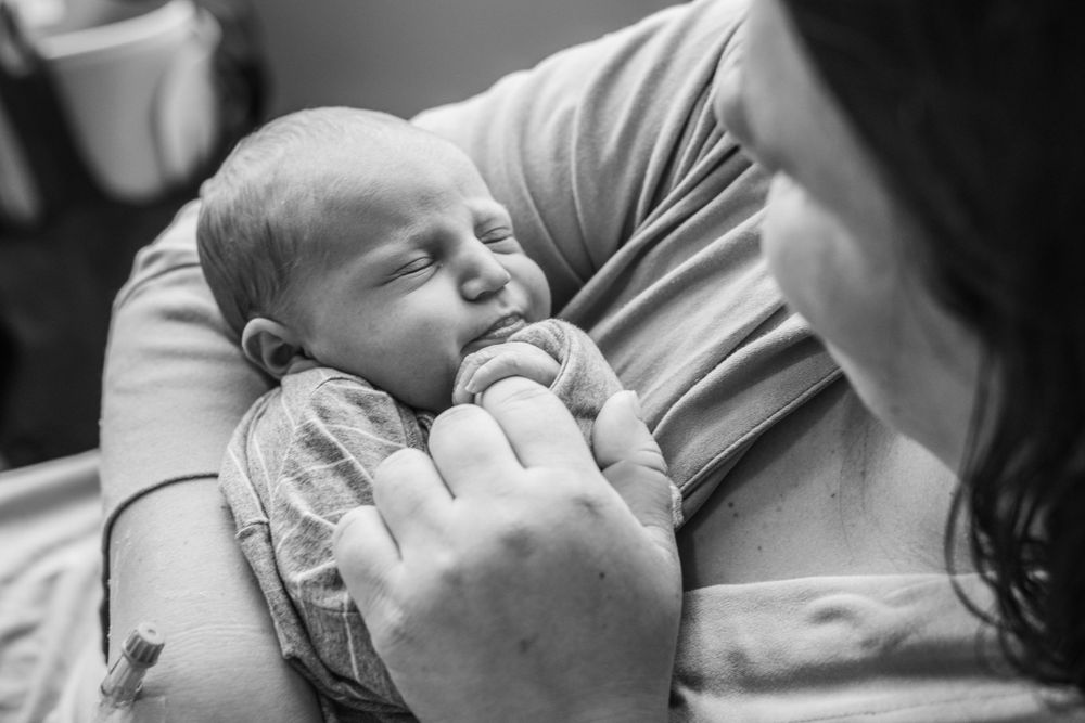 Black and white photo of newborn being gently cradled.