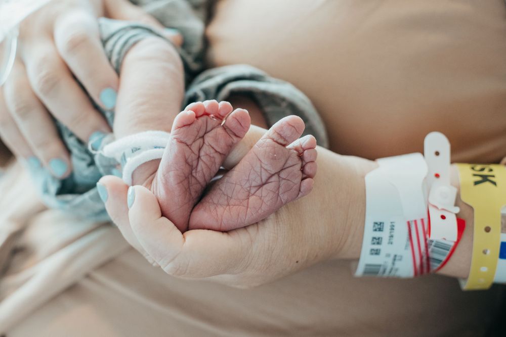 Close up of tiny newborn feet with hospital identification bands.