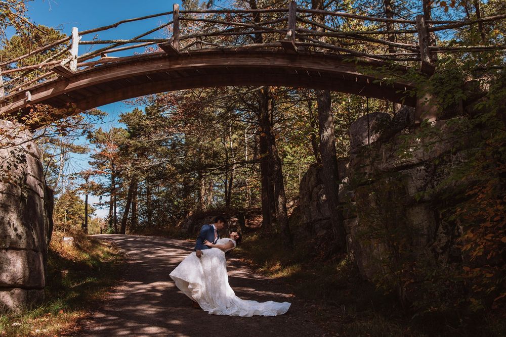 Couple sharing a kiss under a wooden bridge hiking through their Minnewaska state park adventure elopement