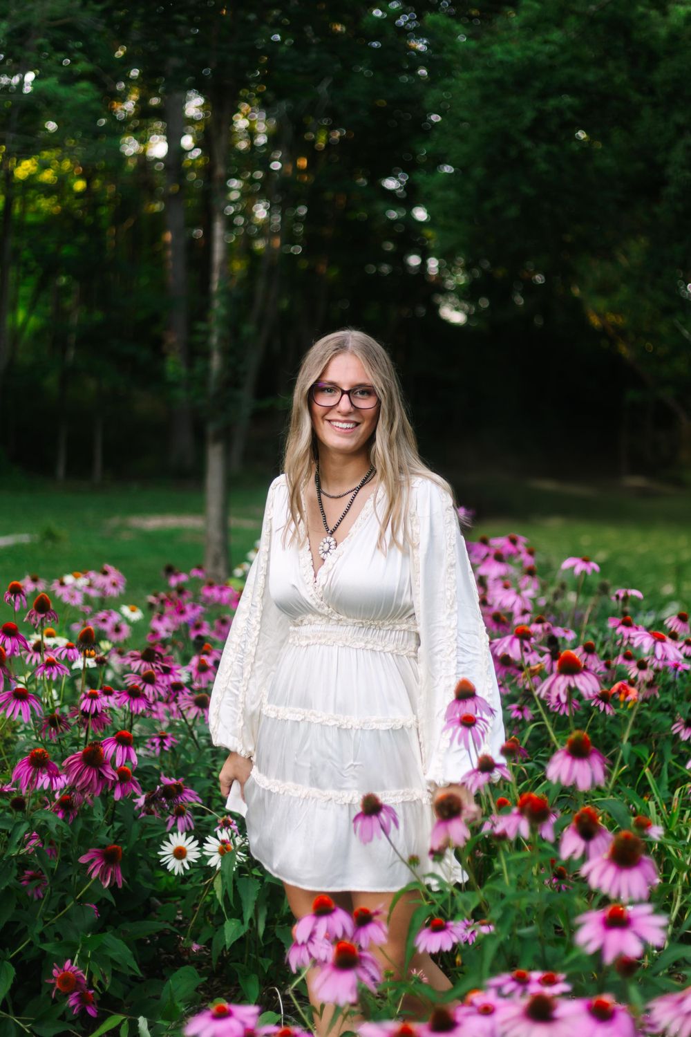 White tiered dress surrounded by blooming purple coneflowers in a lush garden landscape.