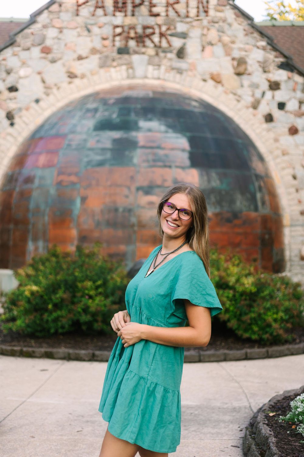 Casual pose in teal dress by stone archway entrance at Pamperin Park.