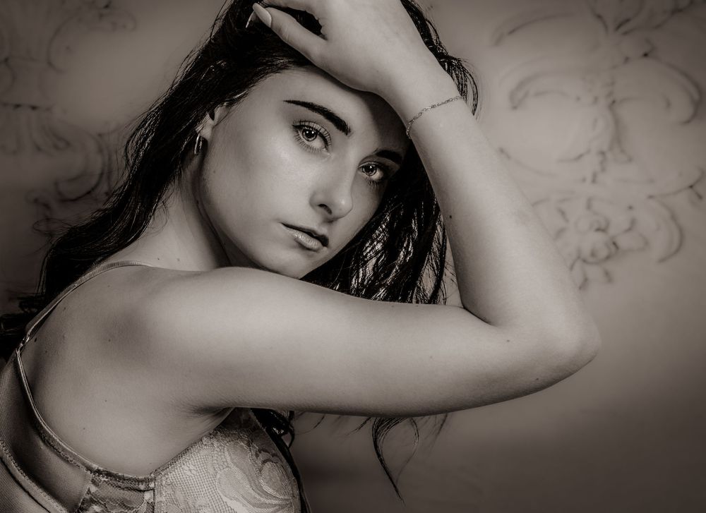 A series of artistic black and white portraits showing dramatic poses against a light floral background.
