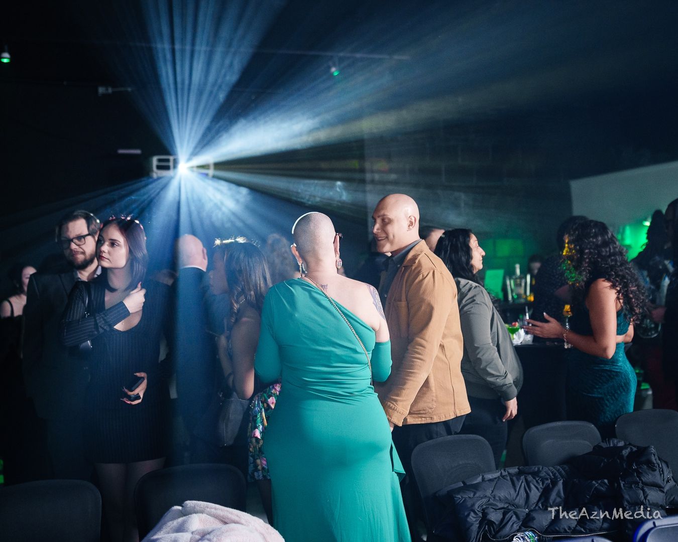 Dance club scene with blue spotlight and crowd in nightclub setting.