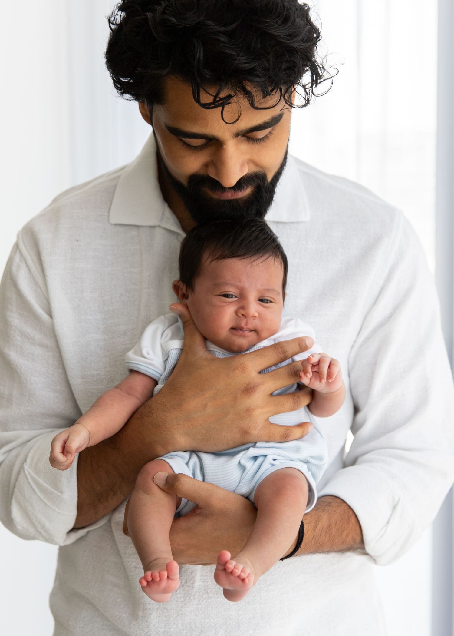 Dad holding newborn baby to his chest facing out during at-home newborn photoshoot