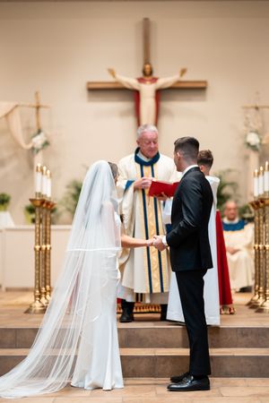 A traditional Catholic church wedding ceremony with priest and couple at the altar.