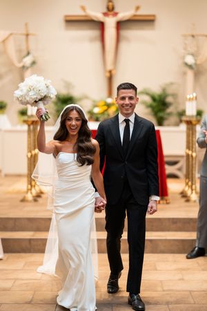 Newlyweds celebrate joyfully while walking down church aisle after ceremony.