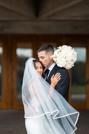 Romantic wedding portraits with bride's veil flowing in soft lighting.