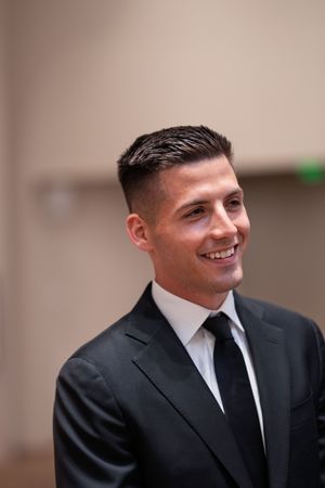 A groom in a black suit and tie smiles warmly in a series of portrait shots.