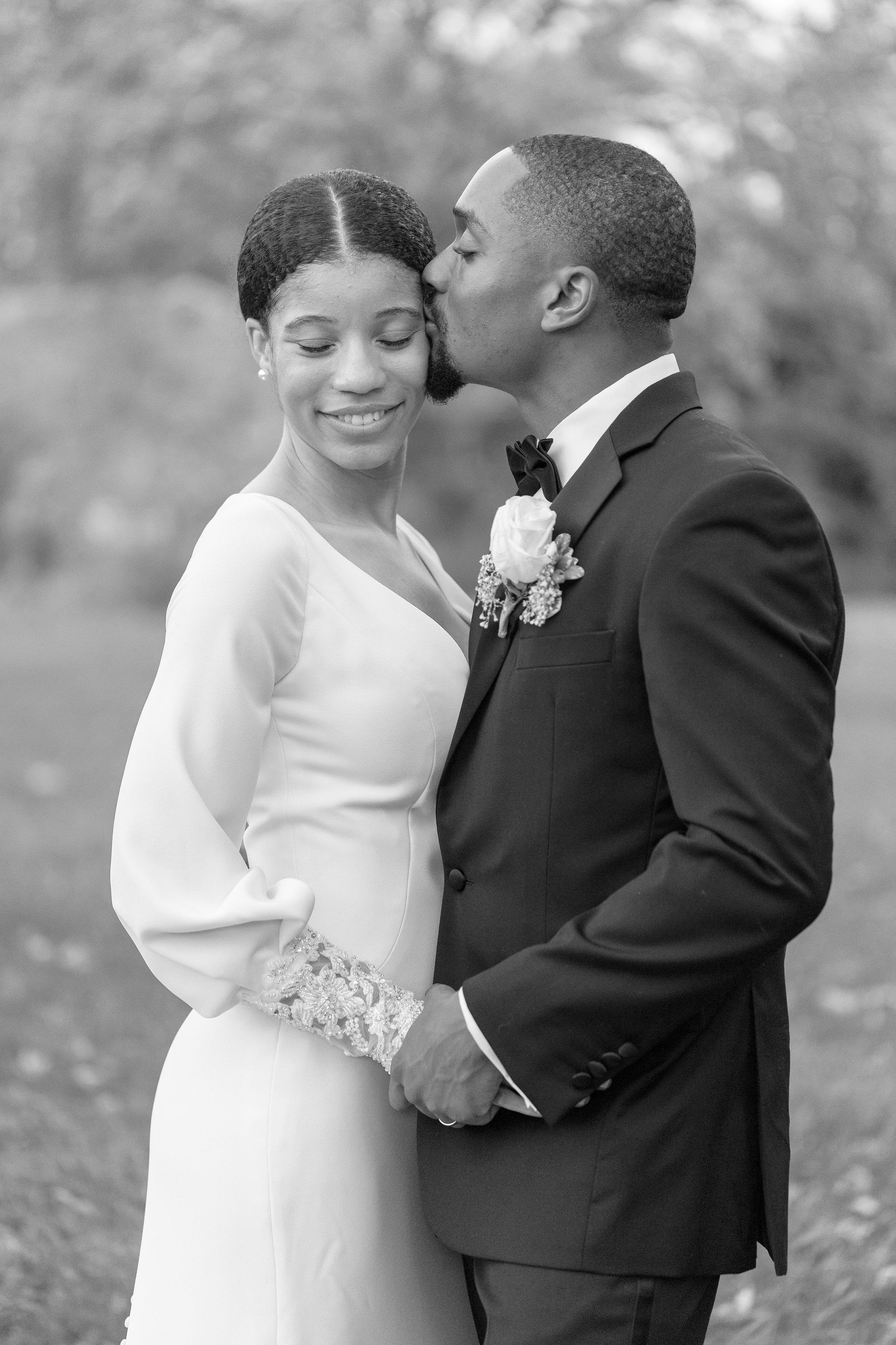 An intimate black and white wedding portrait captured during a tender moment outdoors.