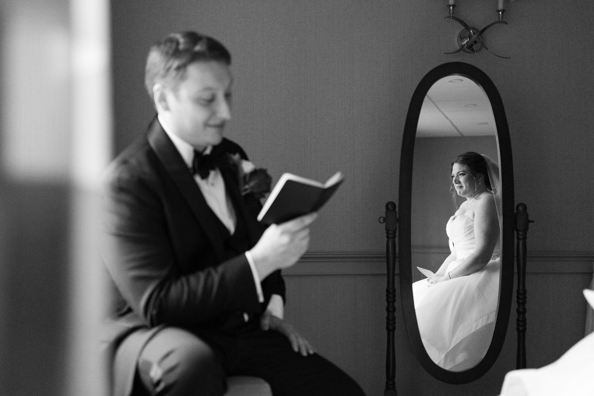 Artistic black and white photo of a reflection in a vintage mirror during wedding preparations.