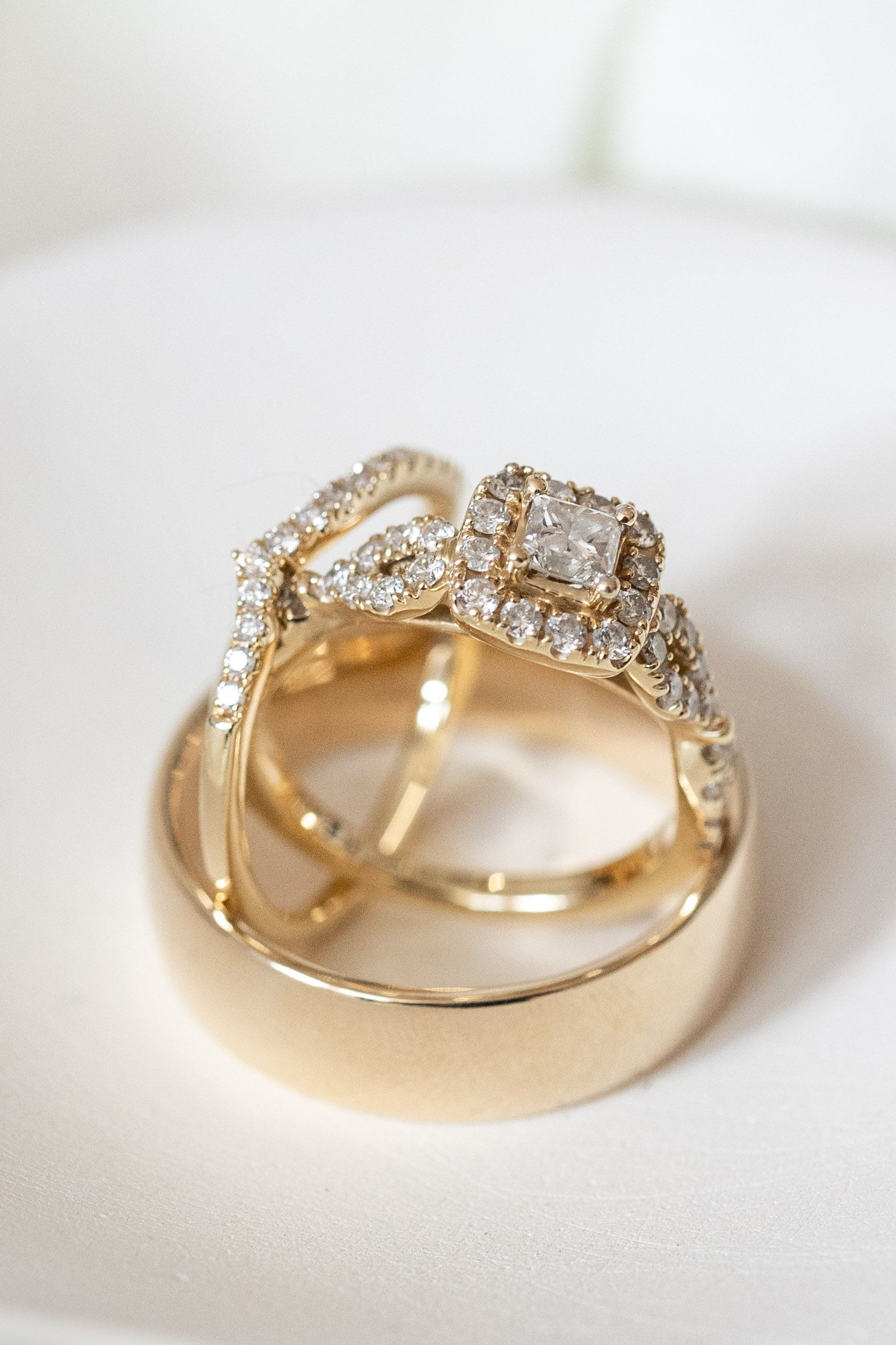 Gold wedding rings with diamonds displayed on white surface showing intricate details.