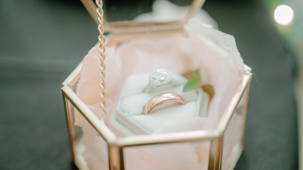 Wedding rings displayed in pink geometric glass terrarium box.