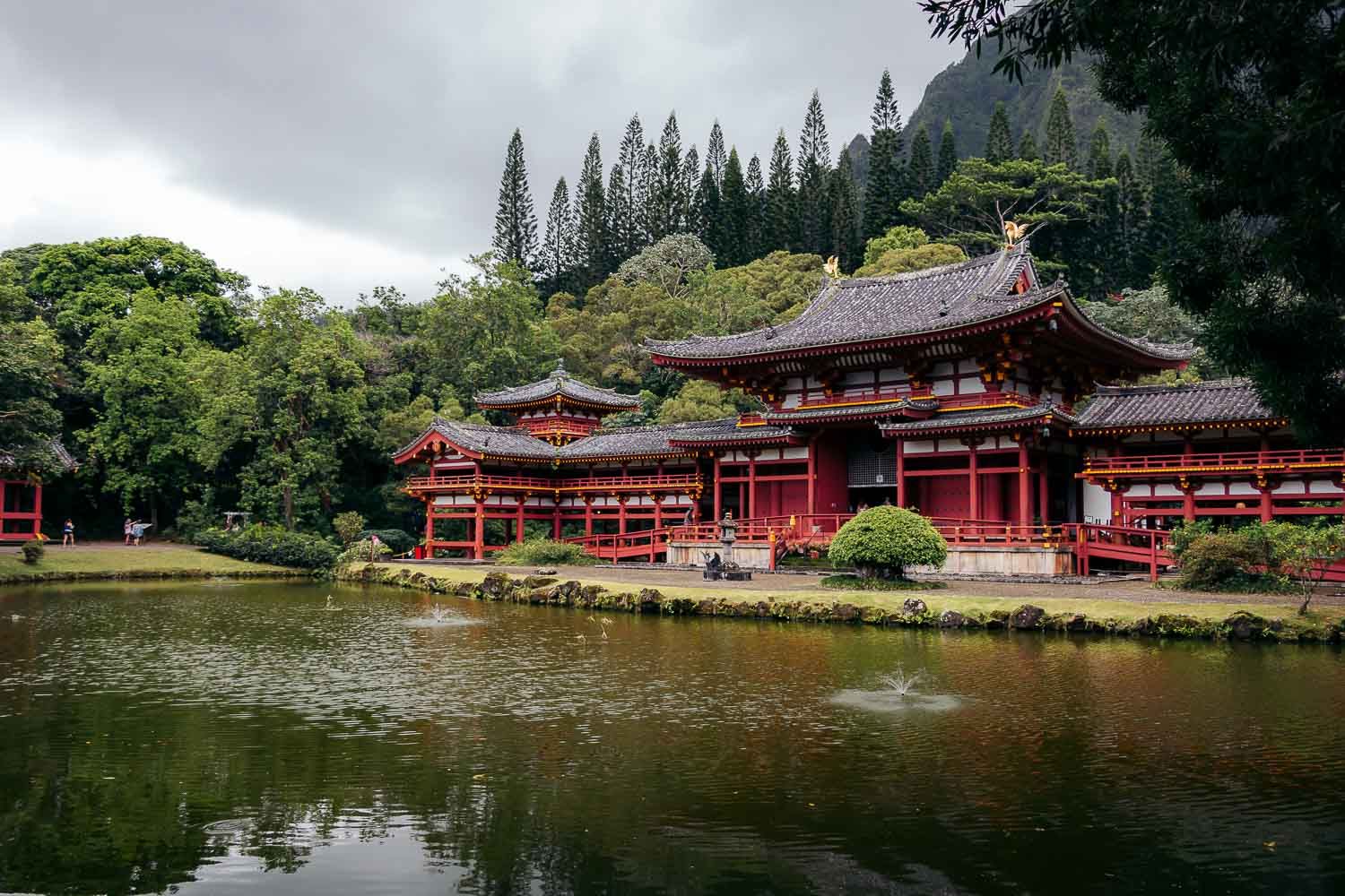 Byodo-In Temple reflects in tranquil pond surrounded by lush Hawaiian landscape.